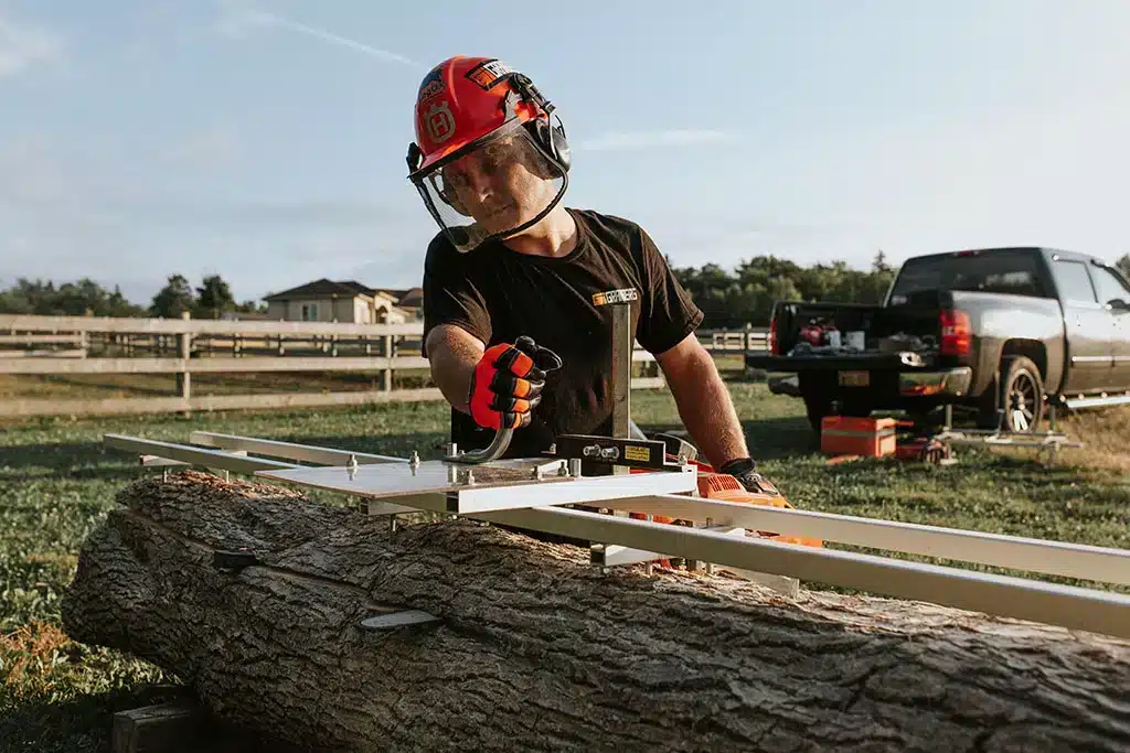 Operator using a Granberg Alaskan MKIV chainsaw mill on a log