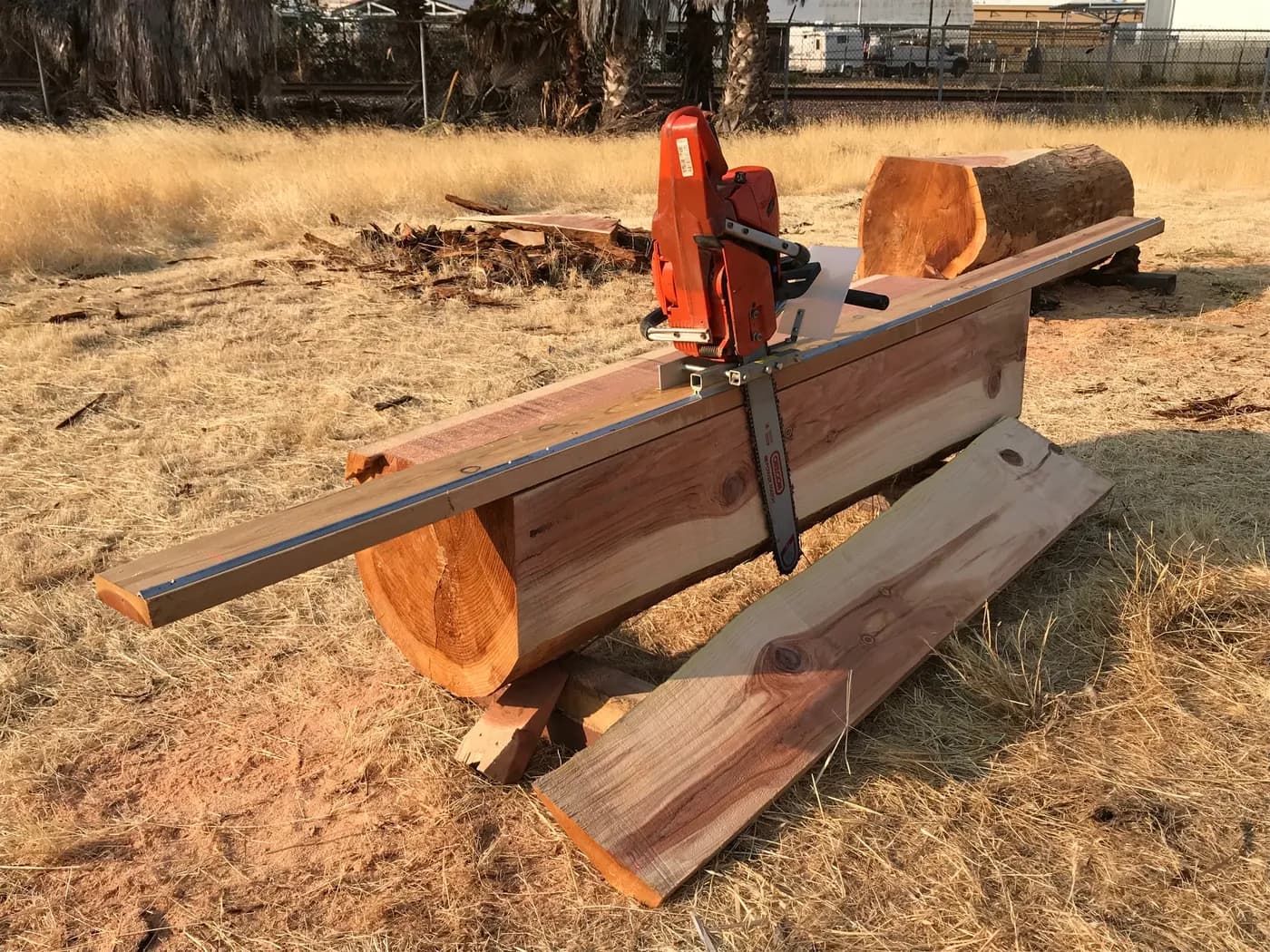 Chainsaw with the Granberg Edging Mill making a vertical cut along a guide rail on a split log