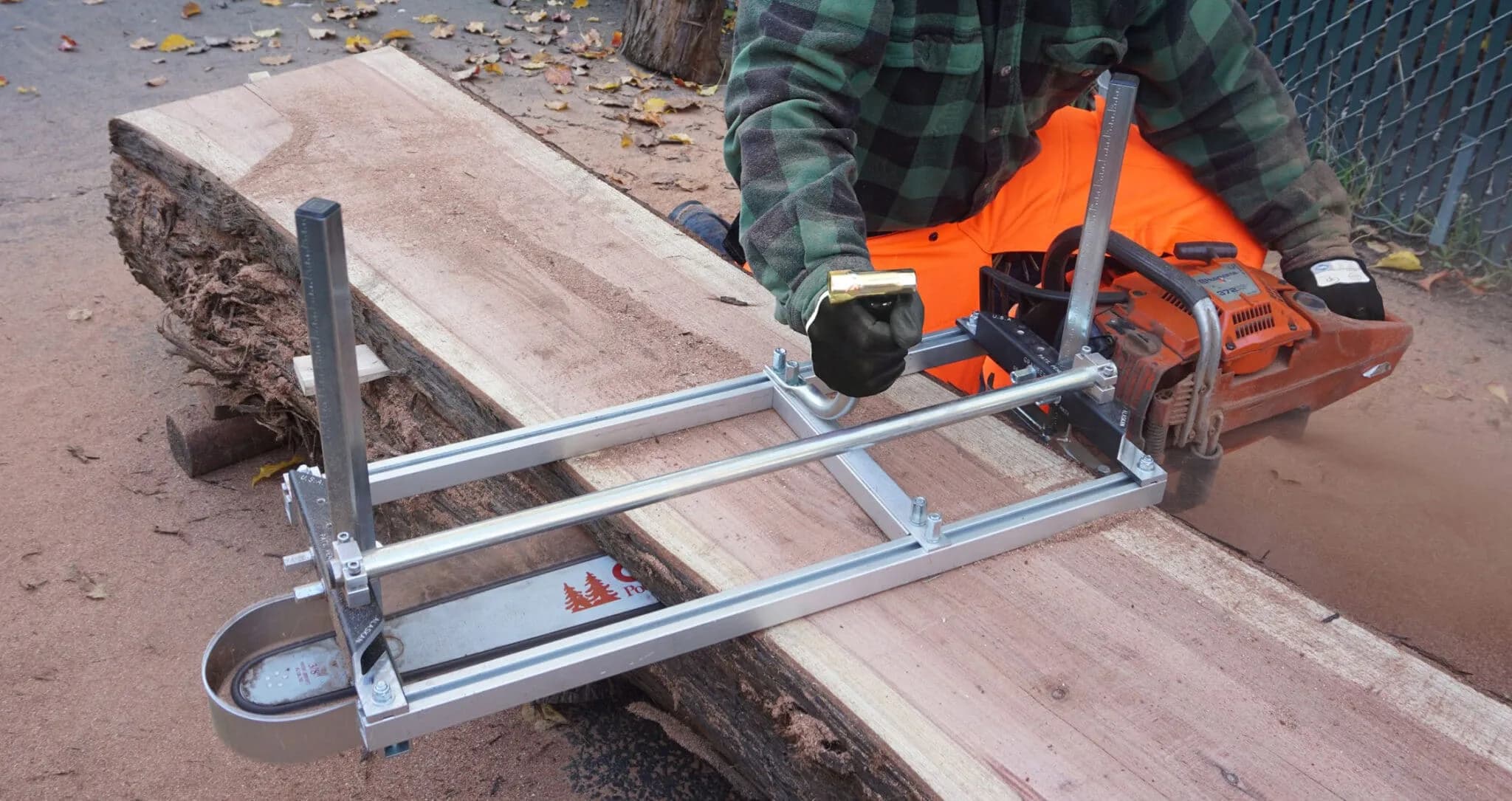 Granberg Alaskan MKIV chainsaw mill clamped to a chainsaw bar, cutting a wide slab from a log