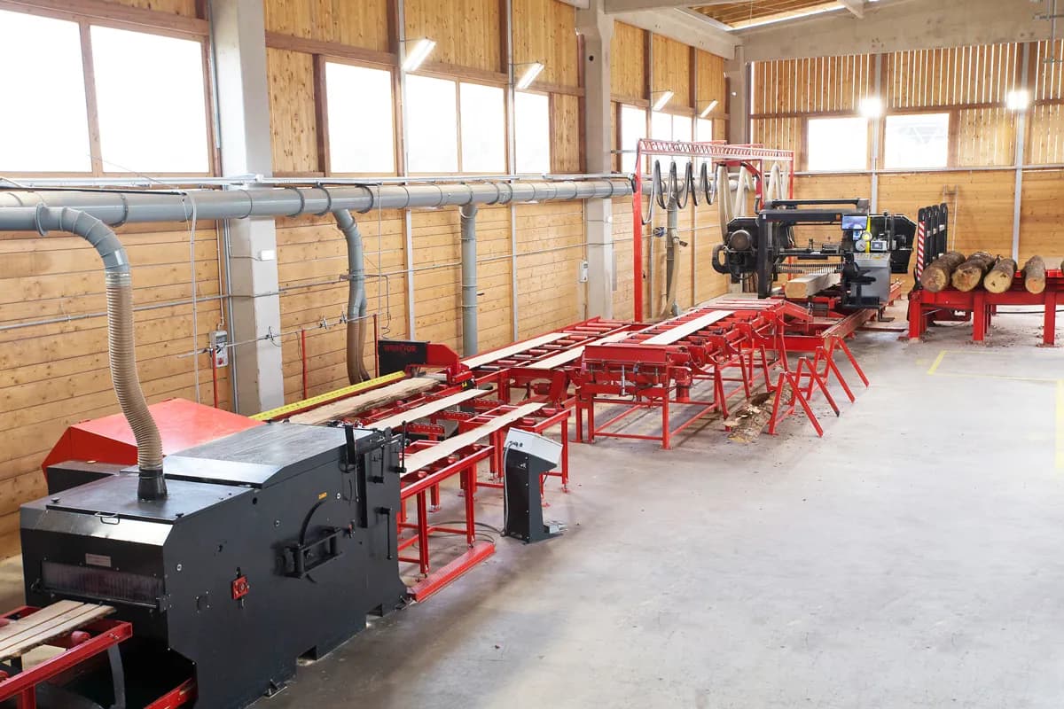 Wravor PROFI sawing line in a timber-clad hall with multi-rip edger, red cross conveyors and headrig