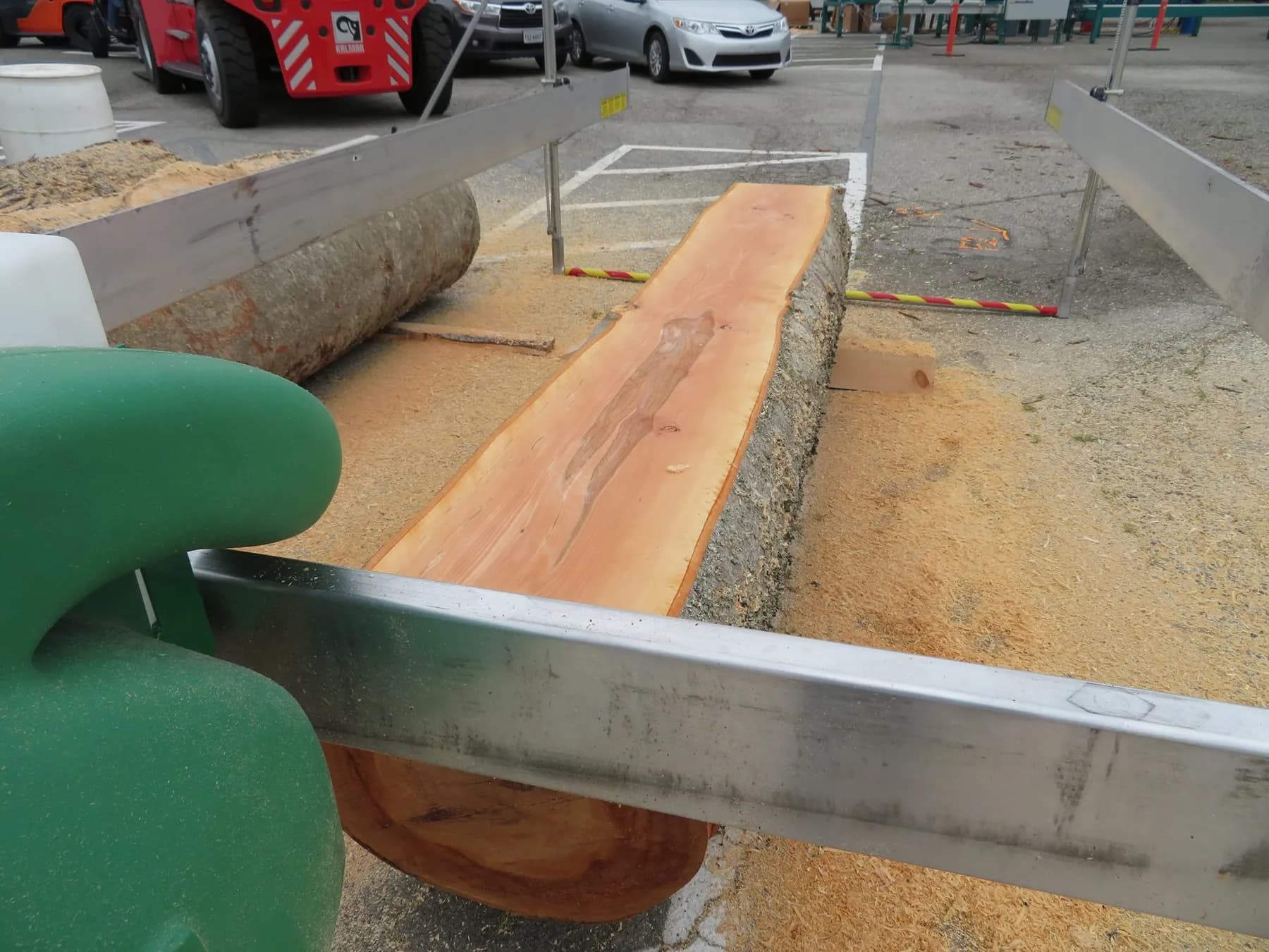 Close-up of a Lucas Mill blade and green saw head cutting along a log