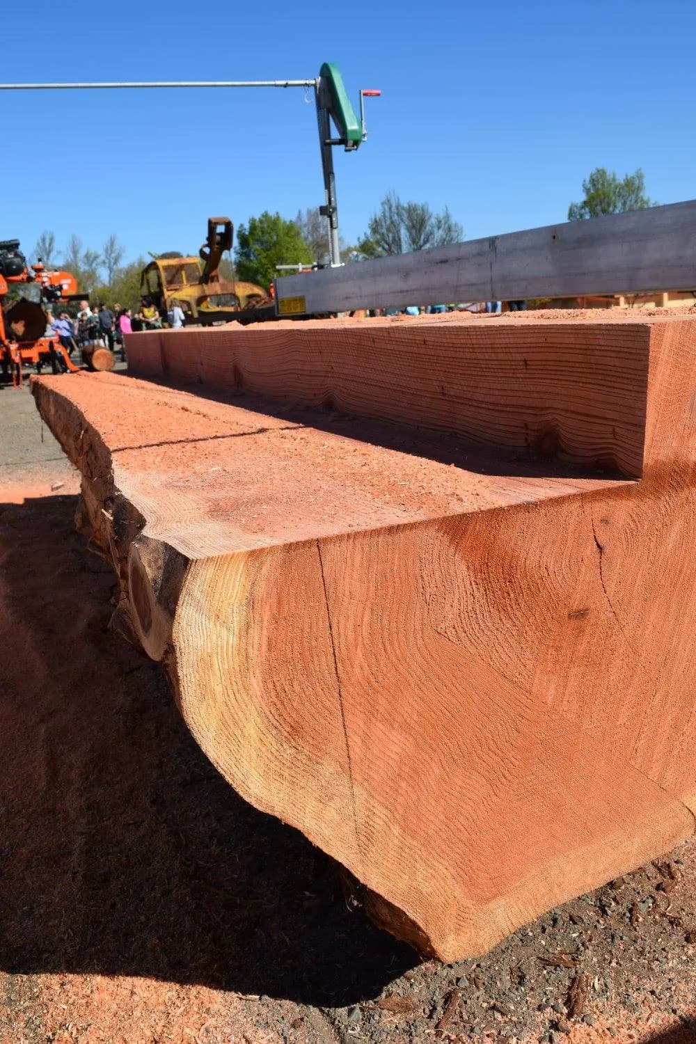 Freshly milled redwood beam beside a Lucas Mill rail