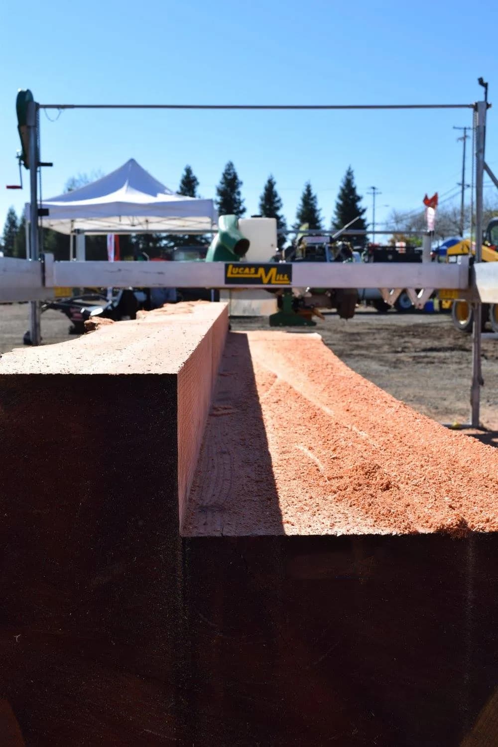 Freshly sawn redwood beam under the rail of a Lucas Mill at a Bailey's show