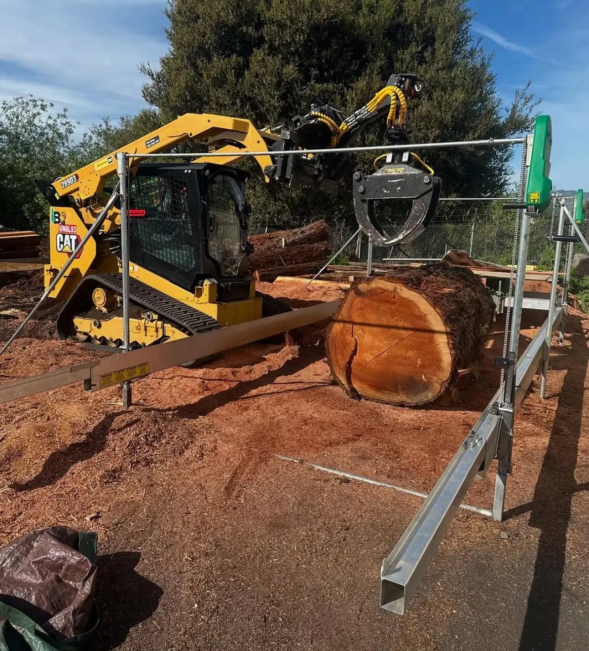 Skid steer setting a log onto a Lucas Mill frame