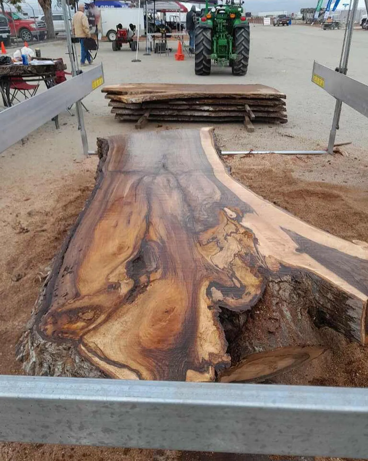Freshly cut figured slab lying on Lucas Mill rails at a show, with stacked slabs behind
