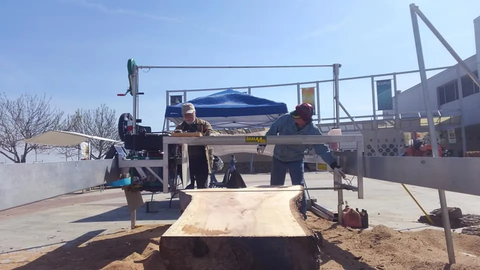 Operators cutting a live-edge slab on a Lucas Mill at a demo
