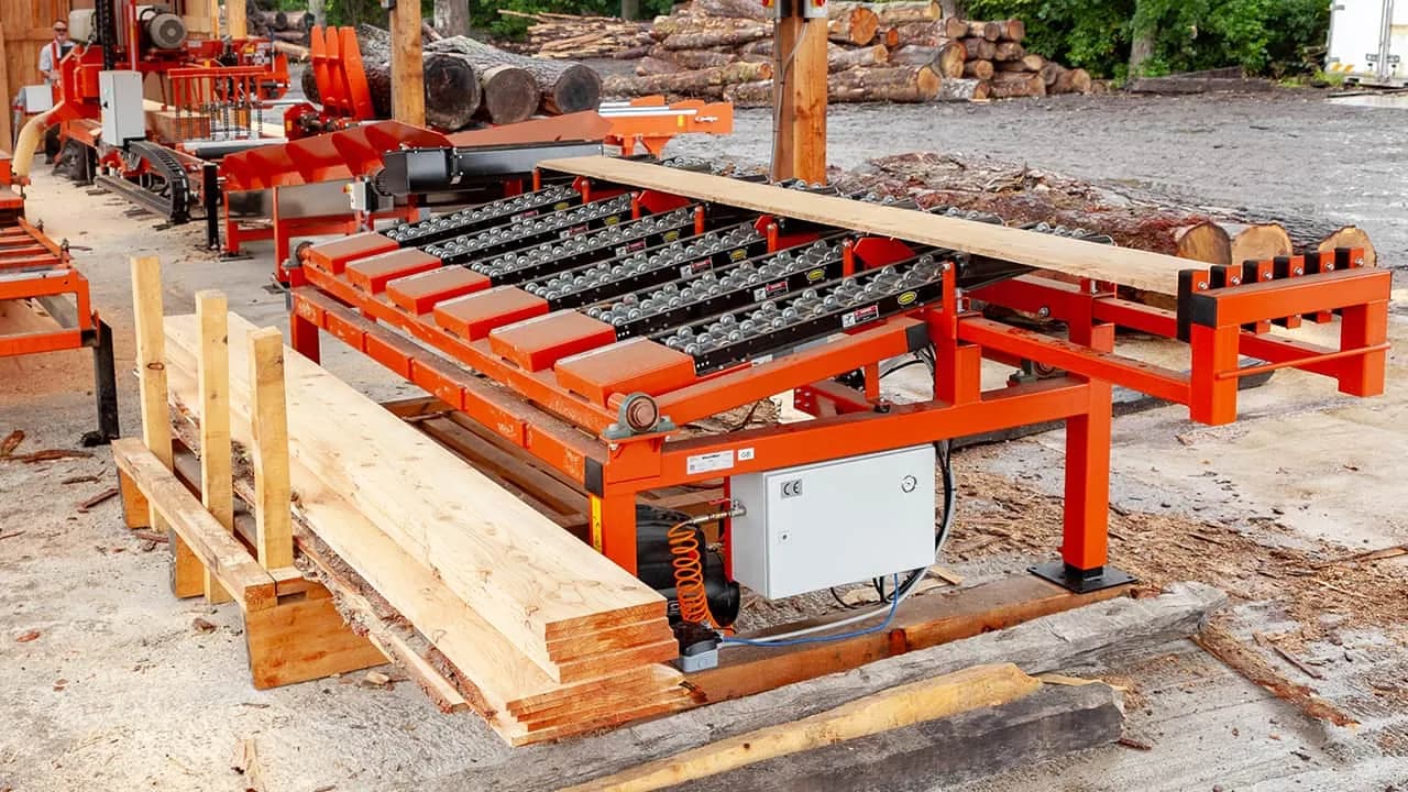 Wood-Mizer transfer table with sawn boards at an outdoor yard