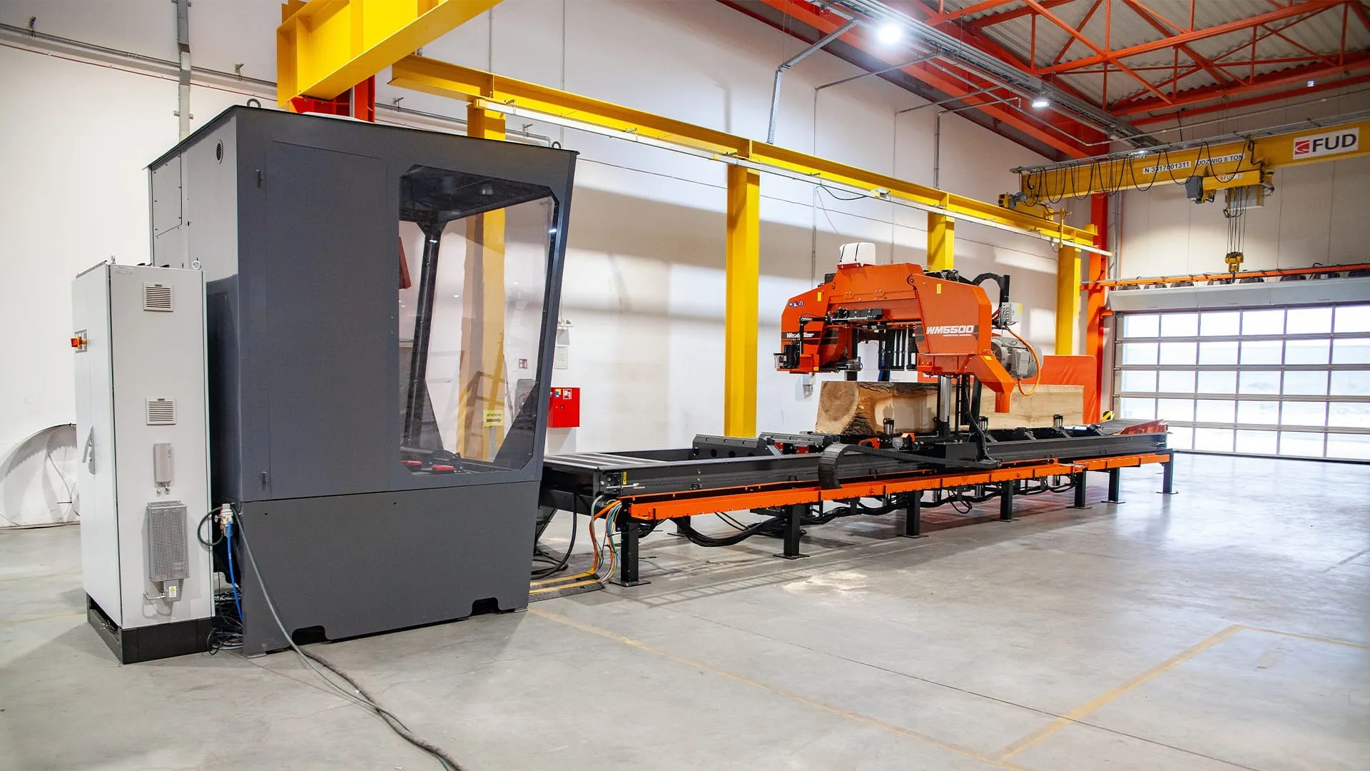 Wood-Mizer WM5500 industrial sawmill with its operator cab and electrical cabinet in a bright hall